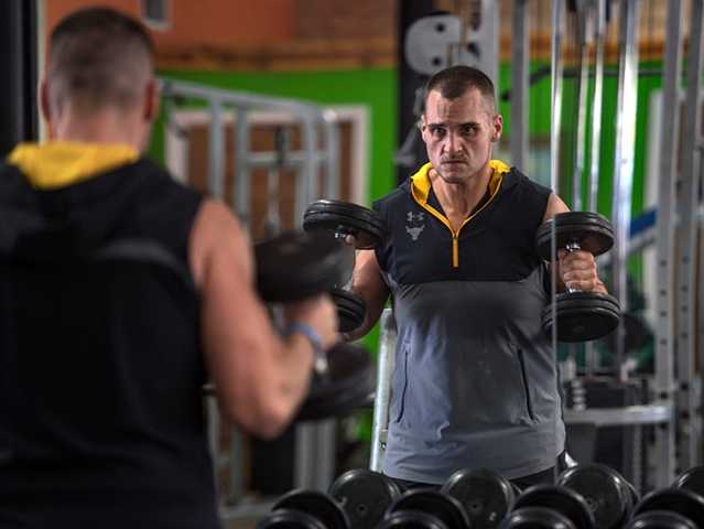 Man wearing a grey and black shirt lifting weights